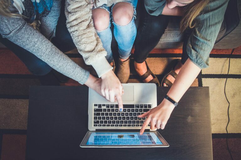 three people pointing happily at a computer screen